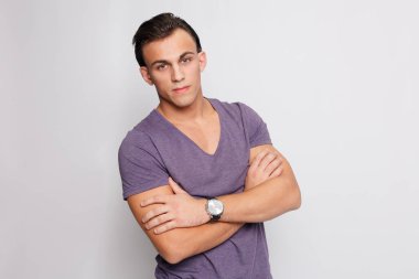 Gri arka plandaki yakışıklı genç adam kameraya bakıyor.