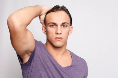 Gri arka plandaki yakışıklı genç adam kameraya bakıyor.