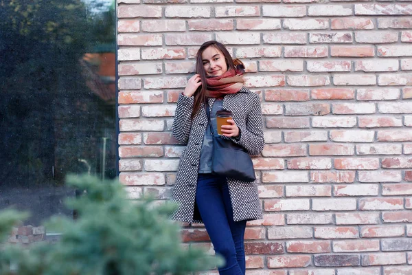 Lady with a cup of coffee walking down the city street — стоковое фото