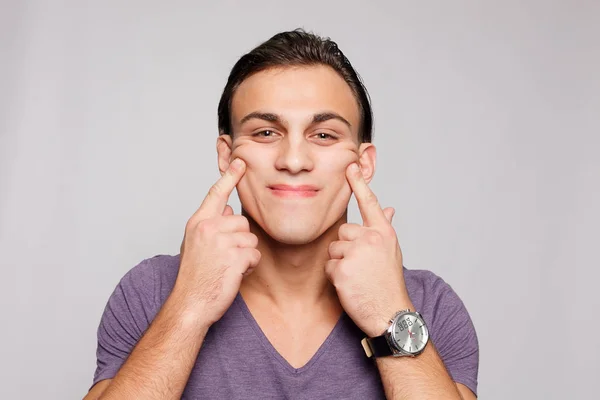 Beau jeune homme sur fond gris regardant la caméra — Photo