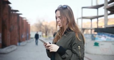 insanlar, sağlık, 4k, diş hekimi ve yaşam tarzı kavramı - açık şık kıyafet sakız genç çekici kadın portresi. Holding ve seyir akıllı telefon gülümseyen genç kadın