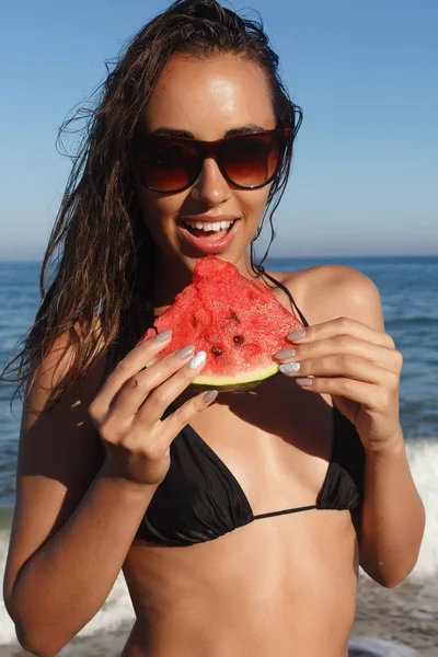 Vacaciones de verano - niña comiendo sandía fresca en la playa de arena —  Fotos de Stock