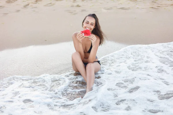 Vacaciones de verano - niña comiendo sandía fresca en la playa de arena —  Fotos de Stock