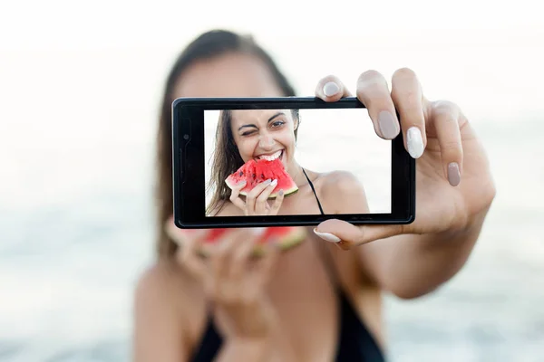 Летние каникулы - молодая девушка ест свежий арбуз на песчаном пляже — стоковое фото