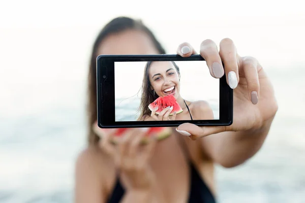 Летние каникулы - молодая девушка ест свежий арбуз на песчаном пляже — стоковое фото