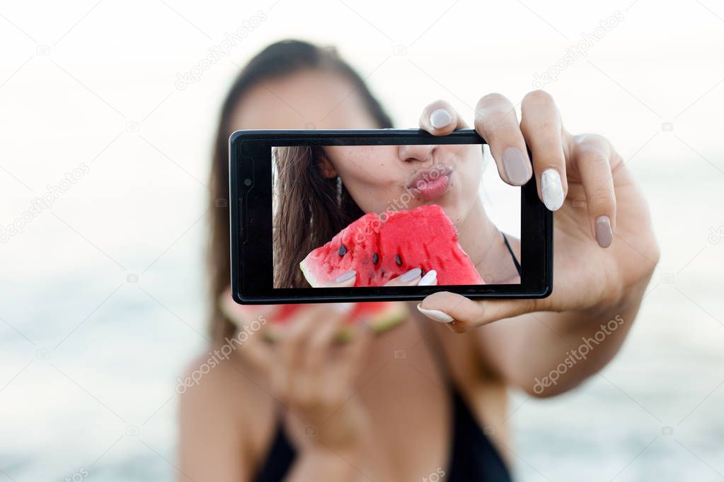 Summer vacation - young girl eating fresh watermelon on sandy beach