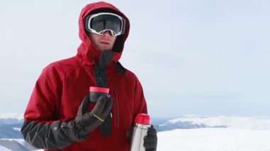 Genç snowboardcu kış kayak merkezinin önünde neşeli bir gülümseme mavi gözler kask spor yaşam tarzı aşırı erkek dağları kayak yapan insanlar. Termostan çay içmek