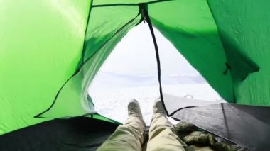 Ayakçı dinleniyor. Kamp sonrası bulutların keyfini çıkarıyor. Dağlarda çadırda oturan bir snowboardcunun portresi.