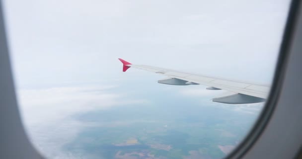 青い空の飛行機の窓からの雲の上の空の景色の素晴らしい映像 飛行機の窓から青い空と白い雲が見えます空から雲を通して地球を見ると — ストック動画