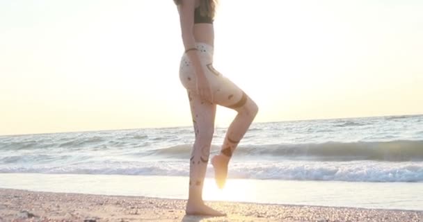 驚くべき日の出で海の上のビーチでヨガを練習ボディスーツの若い女性 フィットネス スポーツ 健康的なライフスタイルのコンセプト スローモーション — ストック動画