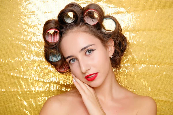 Красивая девушка в бигуди волос изолированы на золото — стоковое фото