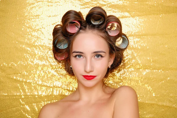 Menina bonita em encrespadores de cabelo isolado em ouro — Fotografia de Stock