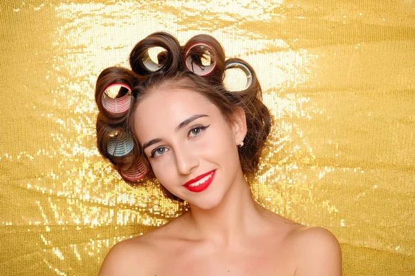 Menina bonita em encrespadores de cabelo isolado em ouro — Fotografia de Stock