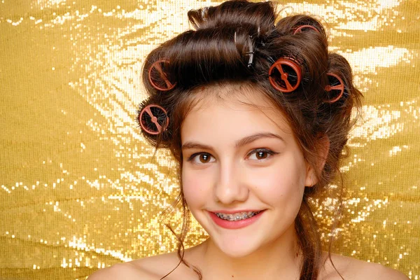 Menina bonita em encrespadores de cabelo isolado em ouro — Fotografia de Stock