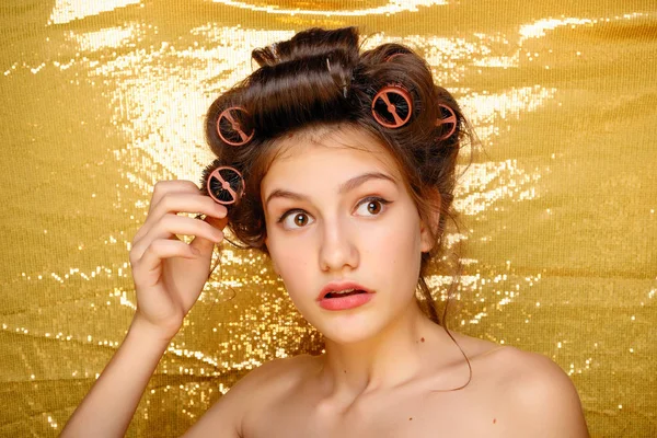 Hermosa chica en rizadores de pelo aislado en oro — Foto de Stock