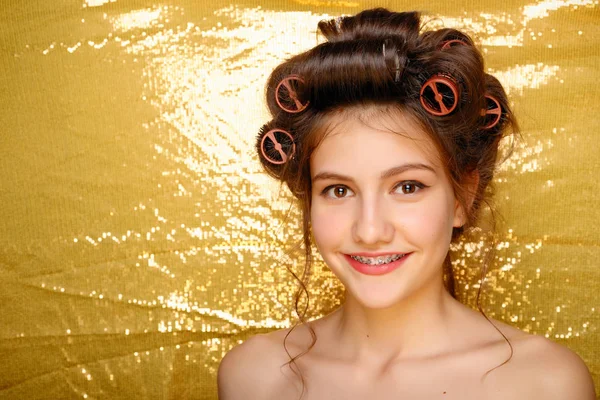 Menina bonita em encrespadores de cabelo isolado em ouro — Fotografia de Stock