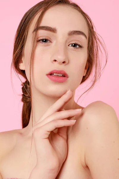 Hermosa joven tocando su piel perfecta sobre fondo rosa . — Foto de Stock