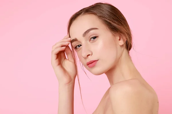Vacker ung flicka röra hennes perfekta hud på rosa bakgrund. — Stockfoto