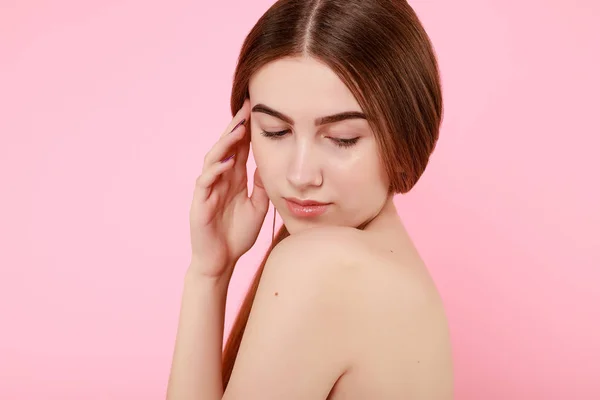 Schöne junge Mädchen berühren ihre perfekte Haut auf rosa Hintergrund. — Stockfoto