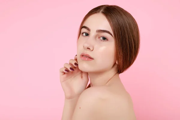 Vacker ung flicka röra hennes perfekta hud på rosa bakgrund. — Stockfoto