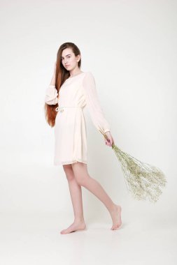 Kıvırcık romantik görünüş, güzel gözler. Beyaz kır çiçekleri ellerinde.