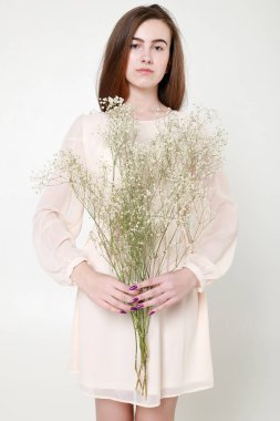 Kıvırcık romantik görünüş, güzel gözler. Beyaz kır çiçekleri ellerinde.