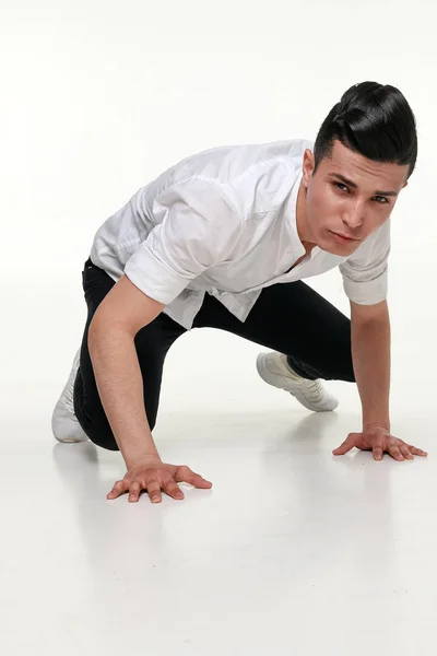 Komea, nuori, trendikäs mies istuu lattialla studiossa — kuvapankkivalokuva