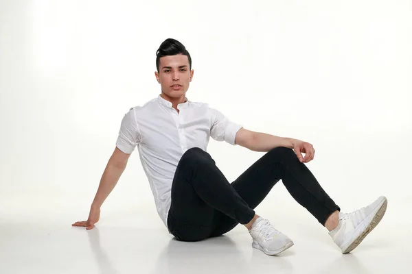 Красивый, молодой, модный мужчина сидит на полу в студии — стоковое фото