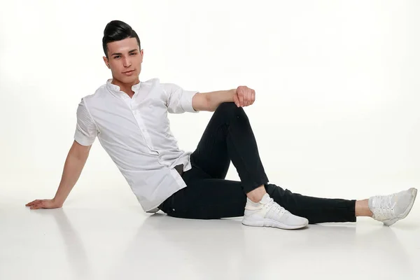 Bello, giovane, uomo alla moda è seduto sul pavimento in studio — Foto Stock