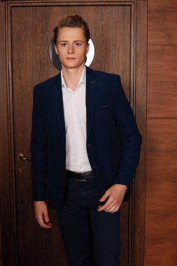 Okul çocuğunun portresi. Resmi olarak siyah takım elbise, kravat.