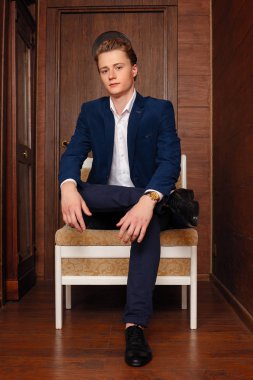 Okul çocuğunun portresi. Resmi olarak siyah takım elbise, kravat.