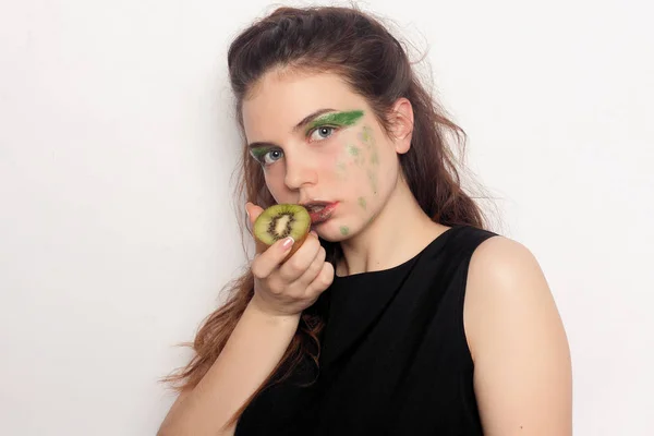 Gelukkig jong meisje eet een halve kiwi — Stockfoto