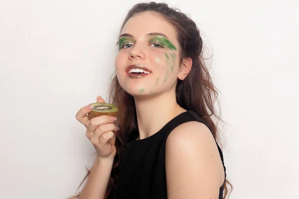 Gelukkig jong meisje eet een halve kiwi — Stockfoto