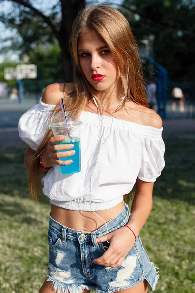 Όμορφη λεπτή κοπέλα πίνει κοκτέιλ. Περπατάει στο δρόμο. — Φωτογραφία Αρχείου