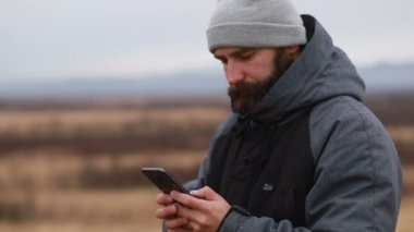 Sakallı, kışlık kıyafetler giyen telefonda konuşan bir adam. Bir yürüyüşçü sırt çantasıyla kış dağlarına gider. Kışın güzel dağlar