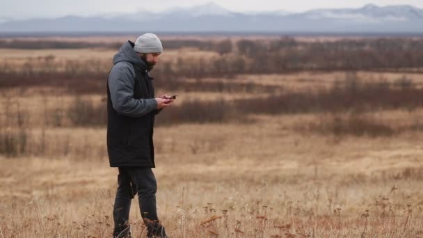 Человек Бородой Зимней Одежде Разговаривает Телефону Турист Идет Зимние Горы — стоковое видео