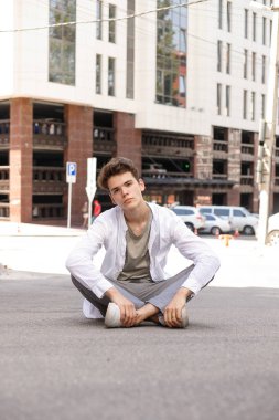 Beyaz gömlekli ve gri pantolonlu şık saç kesimi olan bir erkek model. Modayı takip eden saç stili modern bir iş merkezine yakın. Bir yaz gününde sokakta çekici bir adam..