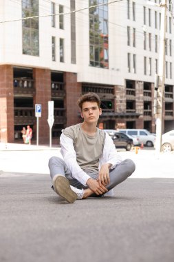 Beyaz gömlekli ve gri pantolonlu şık saç kesimi olan bir erkek model. Modayı takip eden saç stili modern bir iş merkezine yakın. Bir yaz gününde sokakta çekici bir adam..