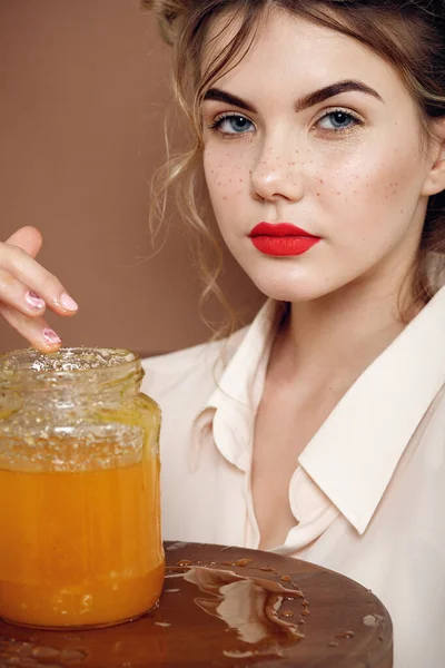 Girl with jar of honey. Healthy food concept, diet, dessert. beautiful girl smiles and touches honey with hands from a jar