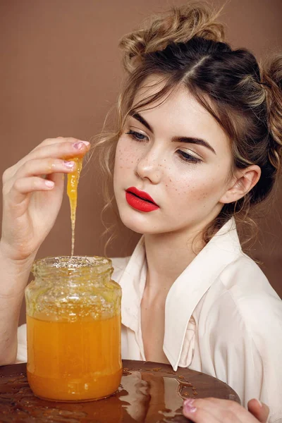 Girl with jar of honey. Healthy food concept, diet, dessert. beautiful girl smiles and touches honey with hands from a jar