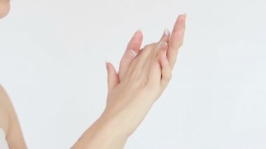 Güzellik, insanlar ve sağlık konsepti - el kremi süren genç bir kadının temiz ve bakımlı elleri, beyaz bir arka planda cilt bakımı. Yakın plan. Şehvetli kadın cildini nemlendirir. 4K, Ağır çekim