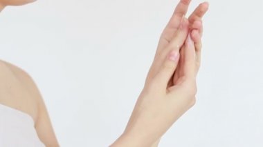 Güzellik, insanlar ve sağlık konsepti - el kremi süren genç bir kadının temiz ve bakımlı elleri, beyaz bir arka planda cilt bakımı. Yakın plan. Şehvetli kadın cildini nemlendirir. 4K, Ağır çekim