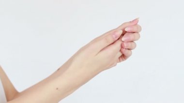 Güzellik, insanlar ve sağlık konsepti - el kremi süren genç bir kadının temiz ve bakımlı elleri, beyaz bir arka planda cilt bakımı. Yakın plan. Şehvetli kadın cildini nemlendirir. 4K, Ağır çekim