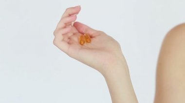 Sağlıklı diyet yemekleri. Elinde balık yağı hapıyla gülümseyen güzel bir genç kadın. - Yakın çekim. Kapsül alıyor. Vitamin ve beslenme takviyeleri. Ağır çekim. Cilt tedavisi konsepti videosu