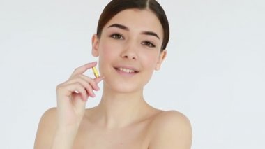 Sağlıklı diyet yemekleri. Elinde balık yağı hapıyla gülümseyen güzel bir genç kadın. - Yakın çekim. Kapsül alıyor. Vitamin ve beslenme takviyeleri. Ağır çekim. Cilt tedavisi konsepti videosu