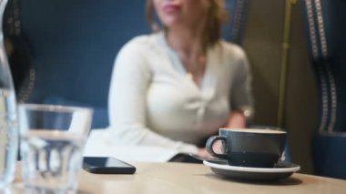 Kafede kahve içen düşünceli güzel bir kadın. Kahve içen genç bir kadının yarım portresi..