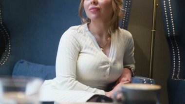 Kafede kahve içen düşünceli güzel bir kadın. Kahve içen genç bir kadının yarım portresi..