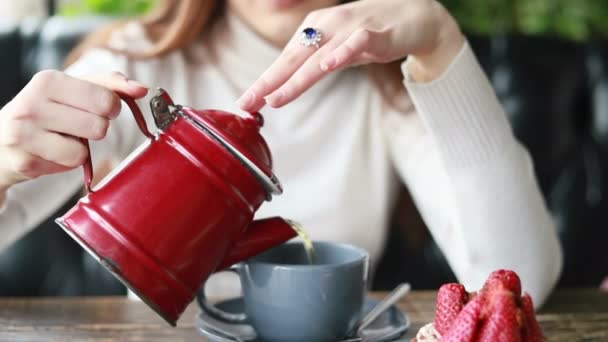 在咖啡店 漂亮的女人把香茶倒进她的杯子里 漂亮而快乐的女人把茶倒在她的杯子里 在餐馆里享用早餐 — 图库视频影像