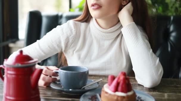 カフェで美しい女性のガジェットと朝のお茶 カップから魅力的な女性の飲み物の快適な顔を閉じます 肯定的な感情を持つカフェでコーヒーやお茶を楽しむ笑顔の女性 — ストック動画