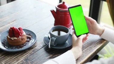Bir kafede yeşil ekranda akıllı telefon, krom anahtar yeşil ekranlı akıllı telefon, yeni teknoloji kavramı kapanıyor.